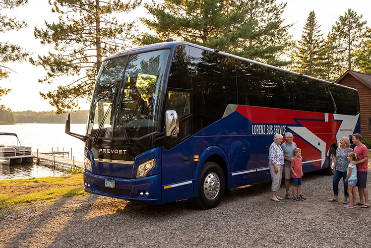 Lorenz Bus Service Prevost motorcoach parked lakeside at sunset with a multigenerational family boarding nearby