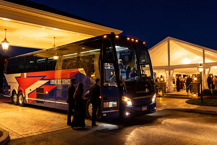 Lorenz Bus Service motorcoach parked outside a lit wedding venue at night, with formally dressed guests boarding for a late-night return shuttle